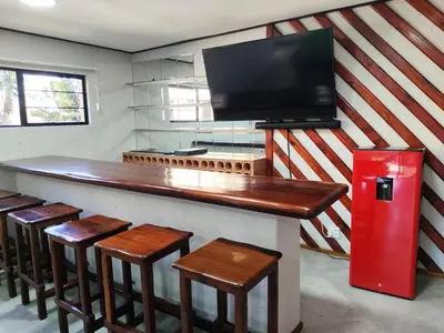 a bar with stools and a tv and a red refrigerator at Letamo View - 5 bedroom house in Hartbeespoort