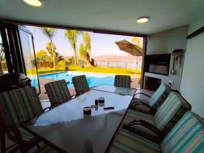a dining room with a table and chairs and a swimming pool at Letamo View - 5 bedroom house in Hartbeespoort