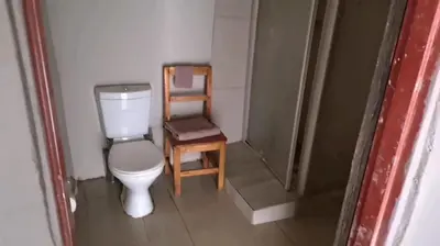 a small bathroom with a toilet and a chair at Dongodzi Lodge in Ha-Lambani