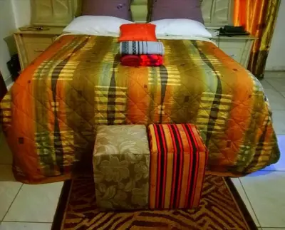 a bed with a colorful blanket and two suitcases on it at Dongodzi Lodge in Ha-Lambani