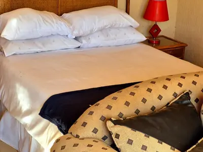 a bed with white sheets and pillows and a red lamp at Dongodzi Lodge in Ha-Lambani