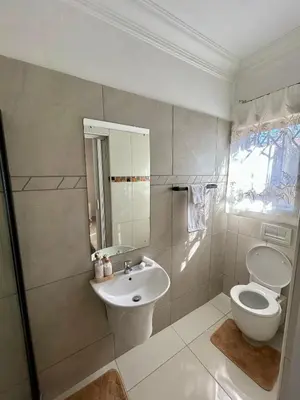 a white bathroom with a toilet and a sink at The Homestead on Nutmeg in Pretoria