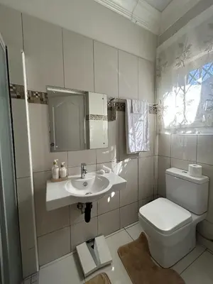 a white bathroom with a toilet and a sink at The Homestead on Nutmeg in Pretoria