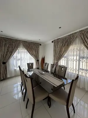 a dining room with a table and chairs and windows at The Homestead on Nutmeg in Pretoria