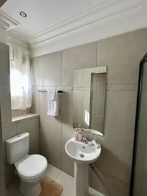 a bathroom with a white toilet and a sink at The Homestead on Nutmeg in Pretoria