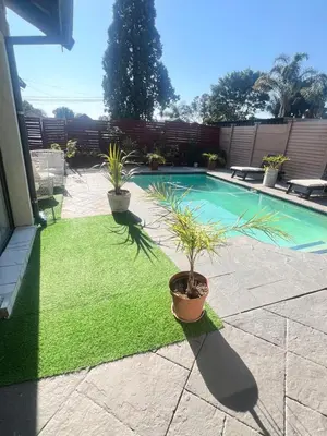 a swimming pool with two potted plants in a yard at 17 Byvanger Luxury Home Deluxe Queen Suite Room 2 in Centurion