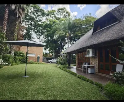 a house with an umbrella next to a yard at Wallace place guest house in Polokwane