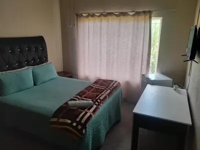 a bedroom with a bed and a couch and a window at Wallace place guest house in Polokwane