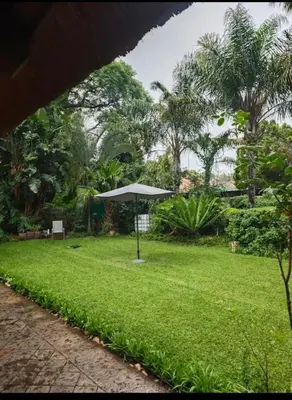 a park with an umbrella in the grass at Wallace place guest house in Polokwane