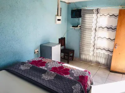 a bedroom with a bed and a refrigerator in it at Joyx BNB in Sibayeni