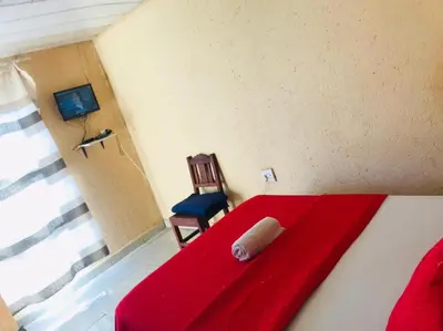 a red bed and a chair in a room at Joyx BNB in Sibayeni