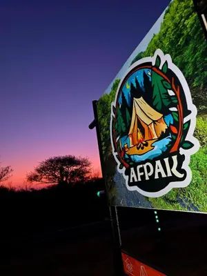 a sign with a tent with a sunset in the background at Afpak in Barberton