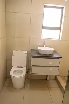 a bathroom with a toilet and a sink and a window at watershed Self catering in Phalaborwa