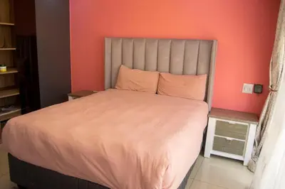 a bedroom with a large bed with an orange wall at watershed Self catering in Phalaborwa