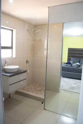 a bathroom with a shower and a sink and a bed at watershed Self catering in Phalaborwa
