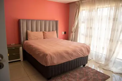 a bedroom with a bed with orange walls and a window at watershed Self catering in Phalaborwa