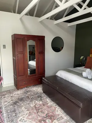 a bedroom with a dresser and a bed and a mirror at Seven in Secunda