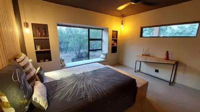 a living room with a bed and a window at Rock'N Round Marloth Lodge in Marloth Park