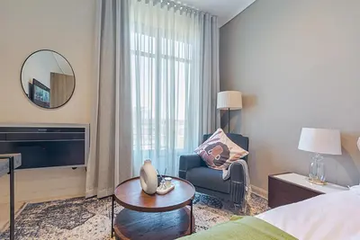 a hotel room with a bed and a chair and a mirror at Menlyn Maine Luxury Studio King Bed Free parking 133 in Pretoria