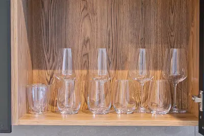 a row of empty glasses sitting on a wooden shelf at Menlyn Maine Luxury Studio King Bed Free parking 133 in Pretoria