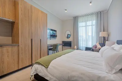 a bedroom with a large bed and a desk at Menlyn Maine Luxury Studio King Bed Free parking 133 in Pretoria