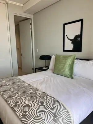 a bedroom with a white bed with a green pillow at Kabazela at Ellipse in Midrand