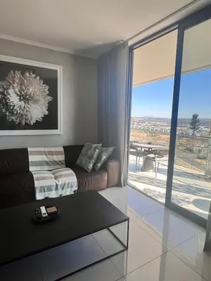 a living room with a couch and a sliding glass door at Kabazela at Ellipse in Midrand