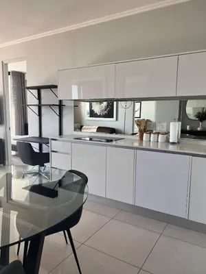 a kitchen with white cabinets and a glass table at Kabazela at Ellipse in Midrand