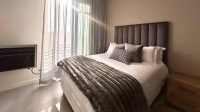 a bedroom with a large bed with a large window at Menlyn Maine Residence - Studio Apartment in Pretoria