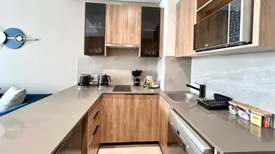 a kitchen with wooden cabinets and a stainless steel sink at Menlyn Maine Residence - Studio Apartment in Pretoria