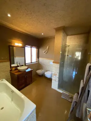 a bathroom with a tub and a sink and a shower at Zebula - African Dream A - Pax 8 in Warmbaths