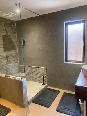 a bathroom with a shower with two mats on the floor at Zebula - African Dream B - Pax 6 in Warmbaths
