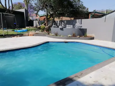 a swimming pool with blue water in a yard at Bendor Escape - Peace Privacy Power in Polokwane