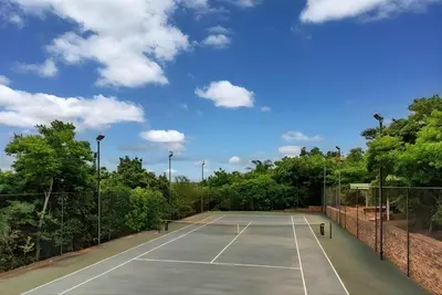 a tennis court with trees and a blue sky at Natures View in Pretoria