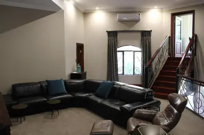 a living room with a black leather couch and stairs at Natures View in Pretoria