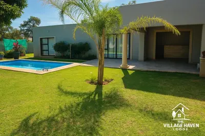 a palm tree in a yard in front of a house at The Village Haven Lodge