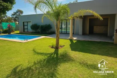 a palm tree in a yard in front of a house at The Village Haven Lodge