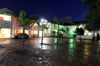 a parking lot at night with palm trees and buildings at Casa Bianca Guest Lodge in Hartbeespoort