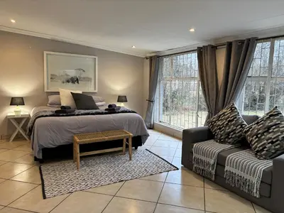a bedroom with a bed and a couch at DullVino Wellington House in Dullstroom