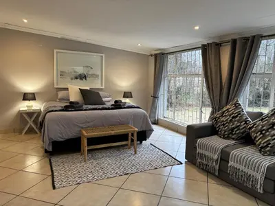 a bedroom with a bed and a couch at DullVino Wellington House in Dullstroom