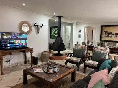 a living room filled with furniture and a flat screen tv at DullVino Wellington House in Dullstroom