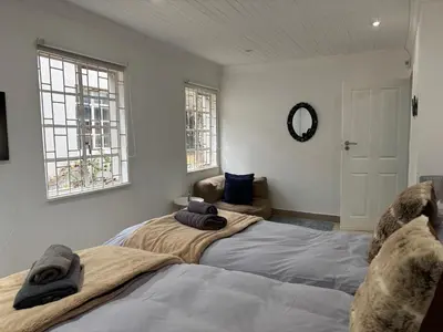 a bedroom with two beds and a couch and two windows at DullVino Wellington House in Dullstroom