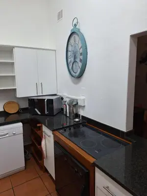 a kitchen with a stove and a clock on the wall at Palm House Accommodation White River in White River