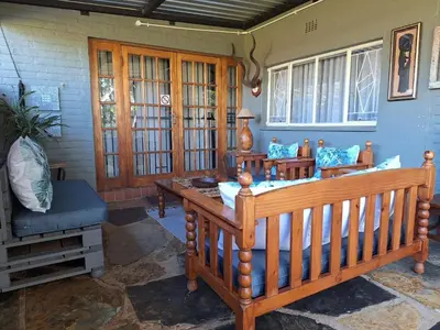 a living room with a wooden bench and a couch at Palm House Accommodation White River in White River