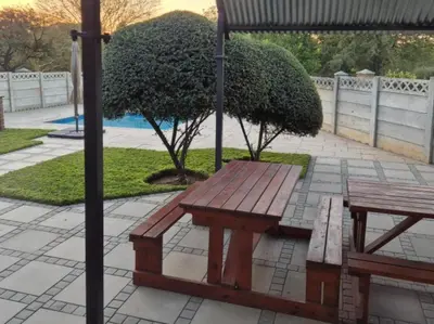 a picnic table and a bench under an umbrella at 5 On Park in Phalaborwa