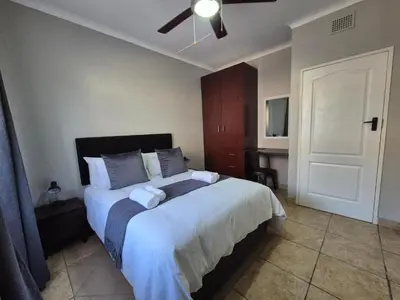 a bedroom with a large bed and a desk at 5 On Park in Phalaborwa