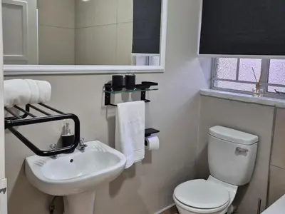 a white bathroom with a toilet and a sink at 5 On Park in Phalaborwa