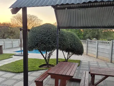 a wooden picnic table and an umbrella on a patio at 5 On Park in Phalaborwa