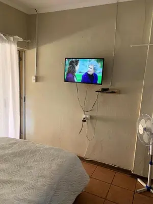 a room with a tv on a wall with a bed at Epizone in Mokopane