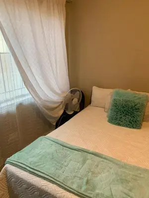 a bed with a green pillow and a window at Epizone in Mokopane